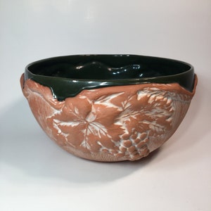 May include: A terracotta bowl with a green glazed rim and a raised design of grape vines and leaves.