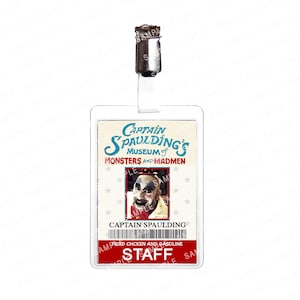 Op de afbeelding: Een doorzichtige plastic personeelsbadge met een metalen clip. De badge bevat de tekst "Captain Spaulding's Museum of Monsters and Madmen" en een foto van Captain Spaulding. De onderkant van de badge luidt "STAFF".