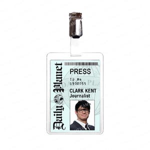 May include: A clear plastic press ID badge with a metal clip. The badge features the Daily Planet logo, the word "PRESS", ID number 1902055, and a photo of Clark Kent, Journalist.