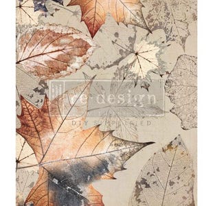 May include: A decorative transfer sheet featuring a pattern of various autumn leaves in shades of brown, orange, and cream. The design includes detailed leaf veins and textures with the text re-design with prima DIY SIMPLIFIED printed in the center.