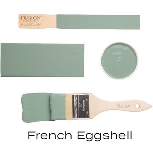 May include: A sample of Fusion Mineral Paint in the color French Eggshell. The paint is a light green color. The image shows a paintbrush, a paint chip, and a small sample of the paint in a container.