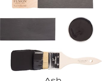 Może przedstawiać: Próbka farby Fusion Mineral Paint w kolorze Popiół. Farba jest ciemnoszara z matowym wykończeniem. Próbka jest pokazana na patyku do farby, pędzlu i w małym pojemniku.