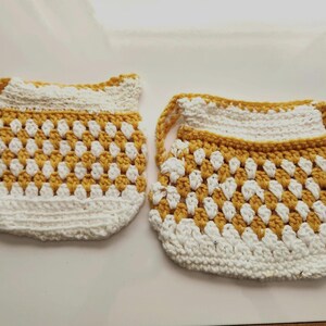 Puede incluir: Dos pequeñas bolsas de ganchillo hechas a mano con un patrón repetitivo en color amarillo mostaza y blanco. Cada bolsa tiene una base blanca sólida, una sección central texturizada con puntos alternos y un borde superior blanco.