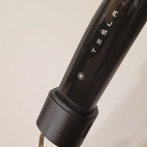 May include: A black Tesla charging cable with a timer dial attached. The dial has numbers from 0 to 60.