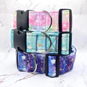 Könnte beinhalten: Drei Hundehalsbänder übereinander gestapelt. Das oberste Halsband hat ein rosa, lila und grünes Aquarelldesign. Das mittlere Halsband ist türkis mit goldenen Sternen. Das untere Halsband ist dunkelblau mit Galaxiedruck.
