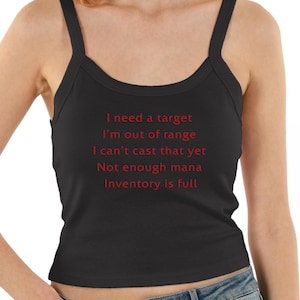 Op de afbeelding: Een zwart hemdje met rode tekst: I need a target, I'm out of range, I can't cast that yet, Not enough mana, Inventory is full. Het kledingstuk heeft brede schouderbanden en een ronde halslijn, wat zorgt voor een eenvoudig ontwerp.