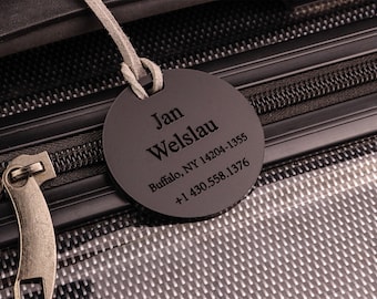 May include: A black luggage tag with the name Jan Welslau, Buffalo, NY 14204-1355 and +1 430.558.1376 printed on it.