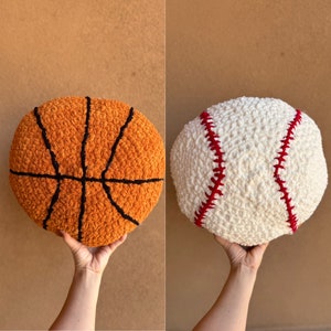 Può includere: Due giocattoli di peluche all'uncinetto a forma di pallacanestro e baseball. La pallacanestro è arancione con cuciture nere e il baseball è bianco con cuciture rosse.