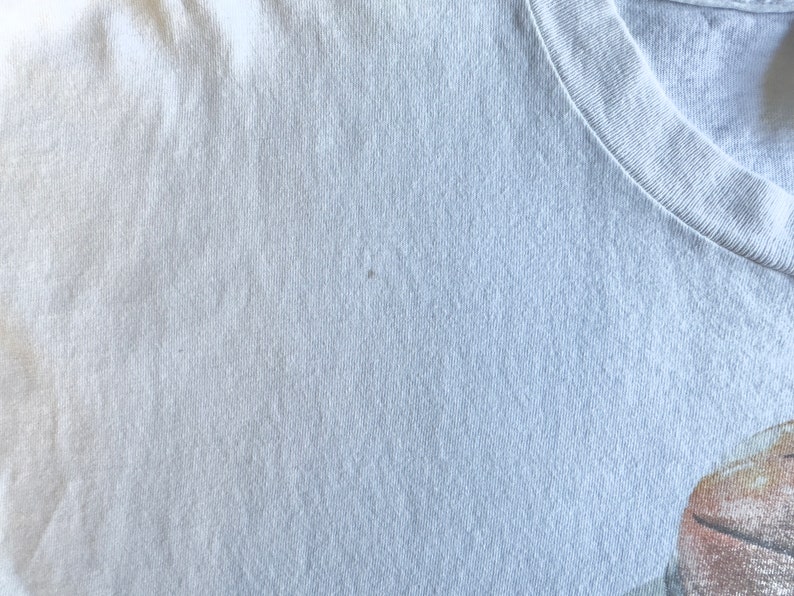 Pode incluir: Um close-up de uma camiseta cinza claro com uma textura lisa. O tecido parece ser de algod&atilde;o.