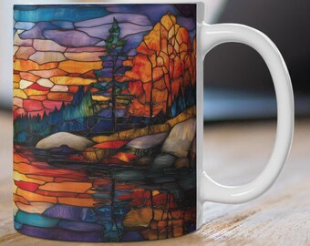 Könnte beinhalten: Weiße Keramiktasse mit einem bunten Glasmalereidesign einer Seenszene mit Bäumen und einer Sonnenuntergangsreflexion.