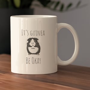 May include: White ceramic mug with a black and white illustration of a guinea pig and the text "It's Guinea Be Okay".