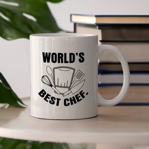 May include: White ceramic mug with a black design that says "World's Best Chef" with a chef's hat and kitchen utensils.