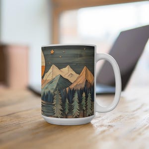 May include: White ceramic mug with a wood-look design featuring a mountain range, trees, and a moon with stars in the night sky.