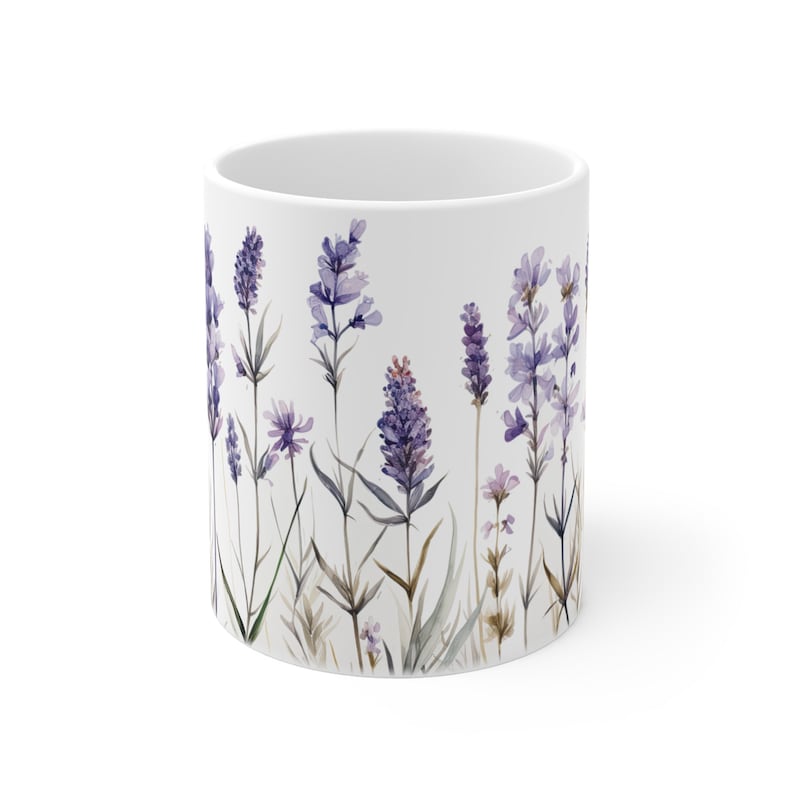 May include: White ceramic mug featuring a watercolor design of lavender flowers. The design includes purple lavender blooms, green stems, and leaves. The mug has a glossy finish and a simple, cylindrical shape.