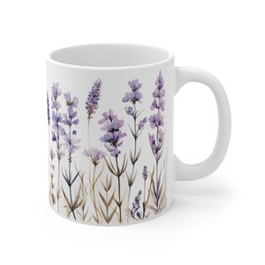 May include: White ceramic mug featuring a watercolor design of lavender flowers in shades of purple and green. The floral design wraps around the mug, with a white handle on the right side. The mug is suitable for hot or cold beverages.