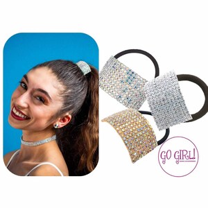 May include: Three sparkly hair ties with a silver, gold, and iridescent finish. The hair ties are made of elastic and have a rhinestone design. The hair ties are arranged in a circle with the brand name "GO GIRL!" in the center.