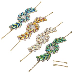 Peut inclure: Quatre ensembles de pinces à cheveux dorées avec des embellissements en cristal iridescent. Chaque ensemble comprend un groupe de cristaux au centre et une rangée de cristaux s'étendant sur le côté. Les cristaux sont dans des tons de bleu, vert, orange et blanc.