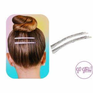 Puede incluir: Dos pinzas para el pelo plateadas con pedrería transparente. Las pinzas son curvadas y tienen un acabado brillante. El texto "GO GIRL!" es visible en la esquina inferior derecha de la imagen.