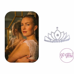 May include: A silver tiara with clear rhinestones and a single larger rhinestone in the center. The tiara is on a white background.