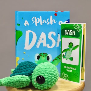 May include: A children's book titled "A Splash of Dash" with a green sea turtle illustration, accompanied by a small book and a green crocheted turtle toy. The small book is titled "DASH" and features a green sea turtle.