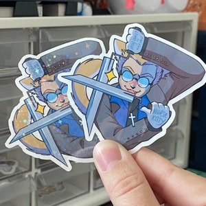 Puede incluir: Dos pegatinas con un personaje de dibujos animados con ojos azules, una camisa azul y una cruz en el pecho. El personaje sostiene dos espadas y tiene un globo de di&aacute;logo que dice "Jes&uacute;s no puede o&iacute;rte en el cielo". La pegatina tambi&eacute;n dice "Nurse Kitty".