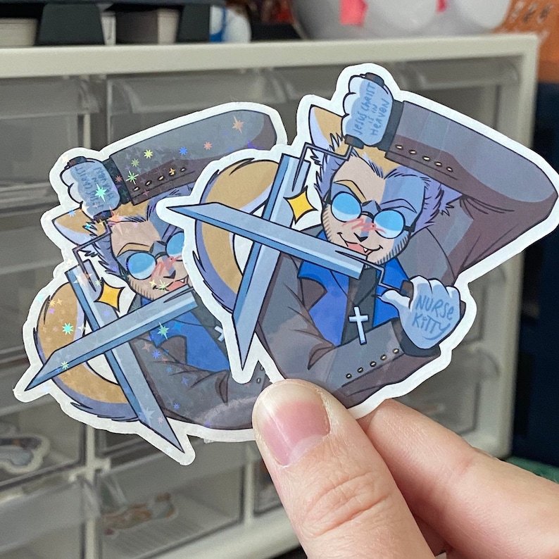 Puede incluir: Dos pegatinas con un personaje de dibujos animados con ojos azules, una camisa azul y una cruz en el pecho. El personaje sostiene dos espadas y tiene un globo de di&aacute;logo que dice "Jes&uacute;s no puede o&iacute;rte en el cielo". La pegatina tambi&eacute;n dice "Nurse Kitty".