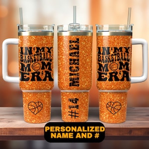 May include: Orange glitter tumbler with a black basketball design and the text "In My Basketball Mom Era". The tumbler has a handle and a straw. The tumbler is personalized with the name "Michael" and the number "14".