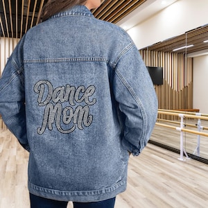 May include: A blue denim jacket with the words "Dance Mom" in rhinestones on the back.