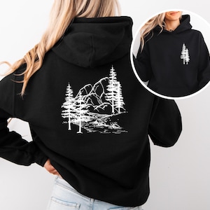 Puede incluir: Sudadera con capucha negra con un gráfico blanco de una cordillera y árboles en la espalda.