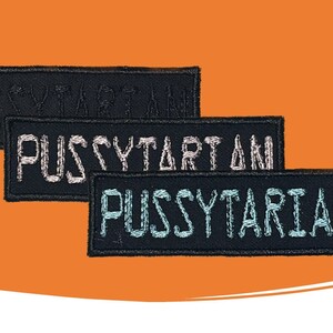 May include: Three rectangular black embroidered patches featuring stitched text. The top patch has black text reading PUSSYTARTAN, the middle patch has white text reading PUSSYTARTAN, and the bottom patch has light blue text reading PUSSYTARIAN.