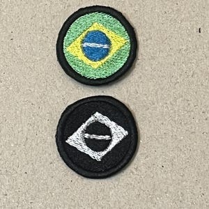 May include: Two embroidered patches. The top patch features the Brazilian flag design, with a green background, yellow diamond, and blue circle with a white stripe. The bottom patch is black with a white diamond design.