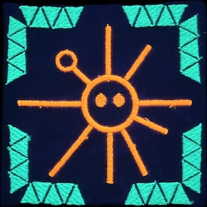 May include: Square patch with a dark blue background, featuring an embroidered orange sun-like design with radiating lines and a small circle. The border is made of green triangles.