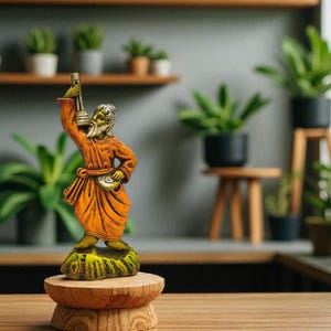 Handcrafted terracotta Baul musician statue with ektara displayed on a wooden pedestal, surrounded by indoor potted plants in a modern green-themed interior.