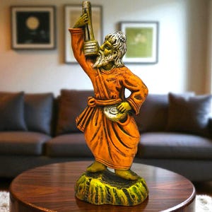 Handcrafted Baul musician terracotta statue holding an ektara, placed on a wooden center table in a modern living room setting.