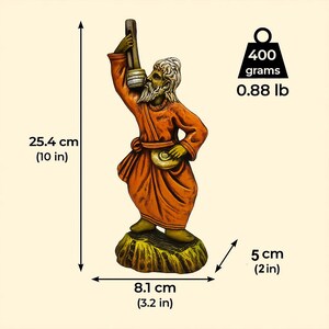 Handmade clay figurine of a Baul folk musician in an orange robe, holding a lantern and a small drum, shown with dimensions 25.4 cm (10 in) tall, 8.1 cm (3.2 in) wide, 5 cm (2 in) deep, and weighing 400 grams (0.88 lb) against a beige background.