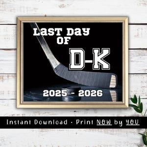 May include: A framed print featuring a black background with a hockey stick and puck. The text reads "LAST DAY OF D-K" in white block letters, with "2025 - 2026" printed below. The frame is light wood, and the design has a sports theme.