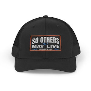 May include: Black trucker hat with a mesh back and a curved brim. The front features a rectangular patch with the text "SO OTHERS MAY LIVE" in white, outlined in orange. Below the text is "VISUAL JACK APPAREL".