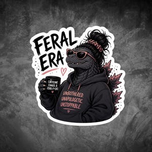 Op de afbeelding: Een sticker met een Godzilla-achtig wezen met een zonnebril en een hoodie. De tekst "FERAL ERA" staat boven het wezen. De hoodie zegt "UNBOTHERED, UNAPOLOGETIC, UNSTOPPABLE." Het wezen houdt een mok vast met "CAFFEINE, CHAOS & ZERO F*CKS."