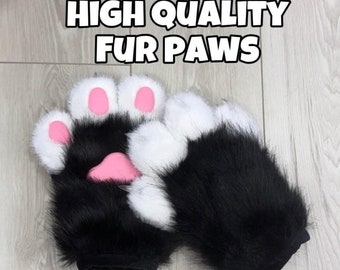 Può includere: Un paio di guanti a forma di zampa in pelliccia sintetica nera e bianca con cuscinetti rosa sulle dita e sul palmo. Il testo HIGH QUALITY FUR PAWS è stampato in bianco con un bordo nero nella parte superiore dell'immagine, descrivendo i guanti.