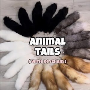 以下が含まれることがあります： 白、黒、グレー、茶色のバリエーションがある、円状に配置されたフェイクファーの動物の尻尾のコレクション。各尻尾には金属製のキーチェーンクラスプが付いています。画像の中央には「ANIMAL TAILS (WITH KEYCHAIN)」というテキストが表示されています。