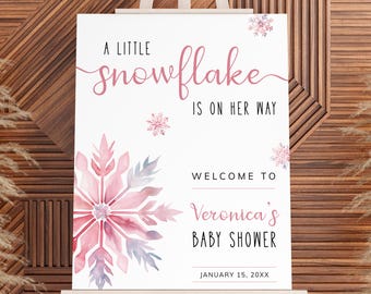 May include: A white sign with a pink snowflake design and the text "A little snowflake is on her way. Welcome to Veronica's Baby Shower. January 15, 20XX".
