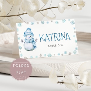 Plantilla de tarjeta de lugar de invierno con un adorable muñeco de nieve azul polvoriento y copos de nieve para la decoración de su mesa con temática de exterior frío / SN02