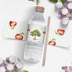 Peut inclure: Une étiquette de bouteille d'eau à rayures vertes et blanches avec un pommier rouge et le texte "A Little Apple" et "Cassie's Baby Shower".