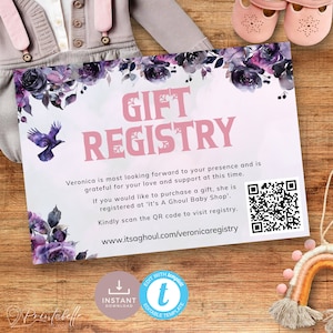 May include: A baby shower gift registry card with the words "GIFT REGISTRY" in pink. The card features floral accents in purple and black, a raven illustration, and a QR code. The card is on a wooden surface.