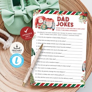 May include: A printable Christmas-themed baby shower game with the title "Dad Jokes". The game features a red and green striped background with a festive Christmas tree and a couple of people wearing Christmas sweaters. The game asks players to guess the answers to 15 corny dad jokes.