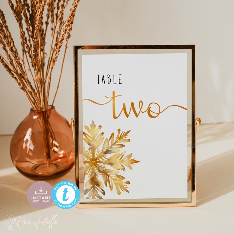 The top half of the sign contains the text, which reads table two. The word table is in a tall, modern font in black and is to the left. Under it in large gold cursive font reads two. It has tails either end that run off the page in both directions.