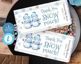 May include: Two printable chocolate bar wrappers with a winter theme. The wrappers feature a watercolor illustration of two snowmen with blue scarves and hats. The text on the wrappers reads "Thank You SNOW much!" and "Veronica's Baby Shower January 12, 2024".