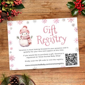 May include: A white gift registry card featuring a snowman illustration in pink and grey. The card displays the words "Gift Registry" in pink script, a QR code, and a website address for online access.