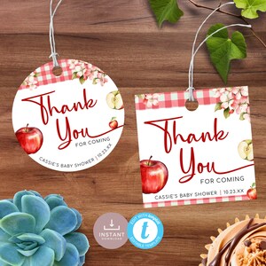 Op de afbeelding: Twee printbare bedankkaartjes voor een babyshower met een rood appel- en roze bloemenontwerp. De tekst luidt "Bedankt voor je komst naar Cassies babyshower 10.23.XX".