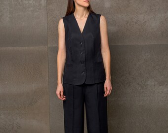 May include: A woman wearing a black pinstripe suit with a sleeveless vest and wide-leg pants.